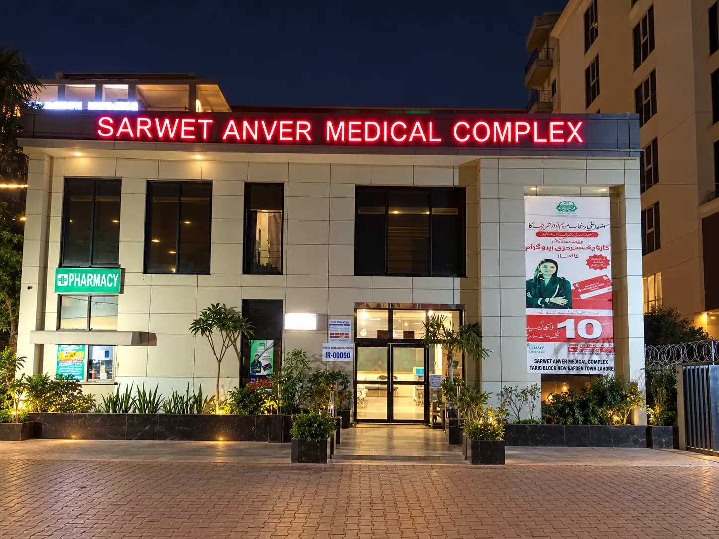 Front entrance of Sarwet Anver Medical Complex at night with its illuminated hospital sign